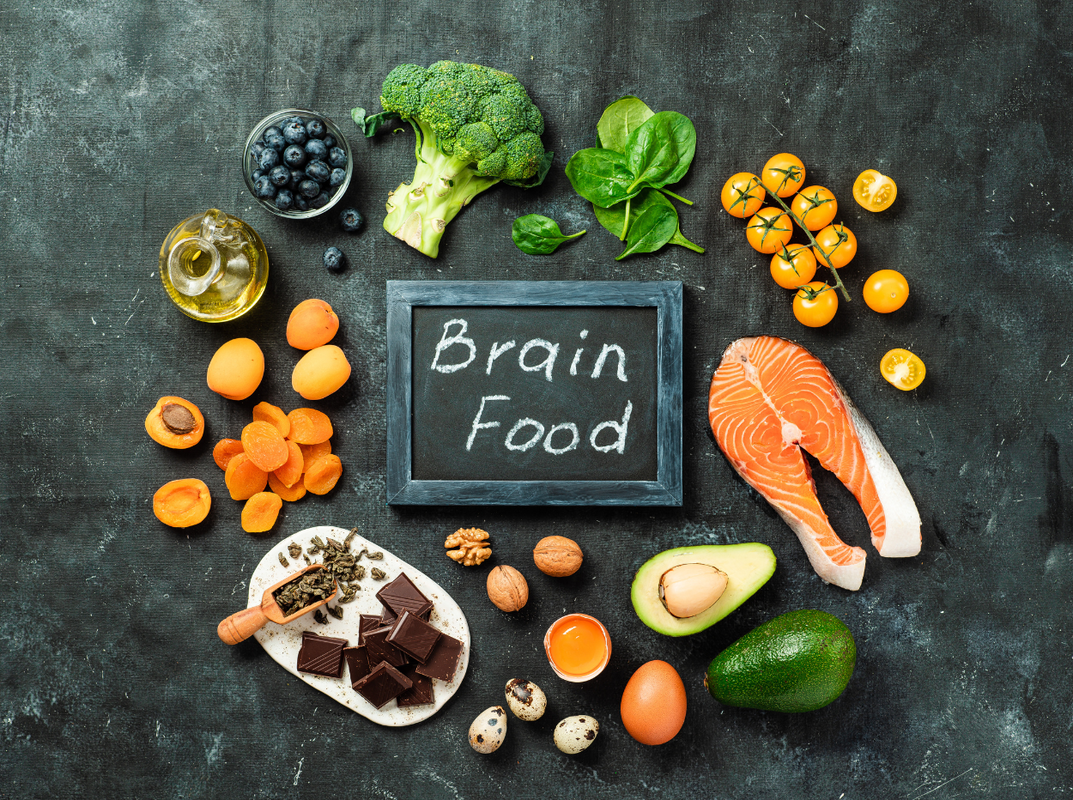 Chalkboard that says brain food with salmon, nuts, vegetables surrounding it
