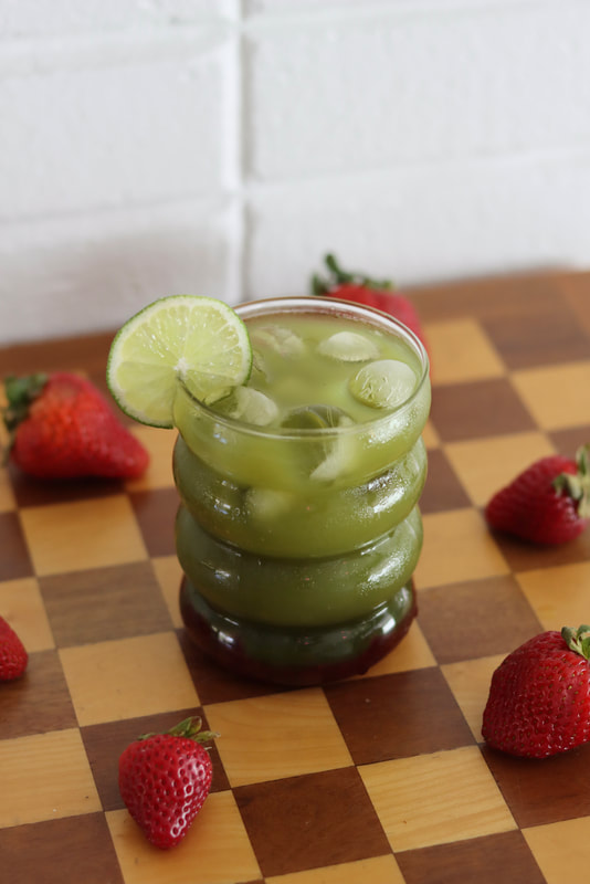 Strawberry-matcha spritzer with checkered background and strawberries